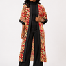 Woman wearing a colorful patterned coat over a black outfit on a white background