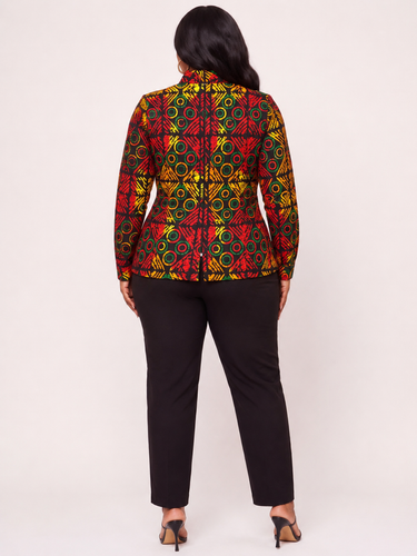 Plus size model wearing a bold red green and yellow geometric Ankara print button down top with long sleeves white contrast buttons high mock neck and peplum hem styled with black straight leg pants