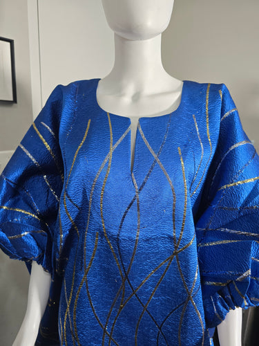 Blue dress with gold and black patterns on a mannequin against a neutral background