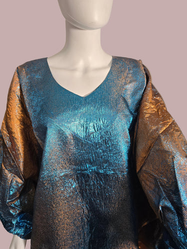 Mannequin wearing a metallic blue and gold dress with a blurred background