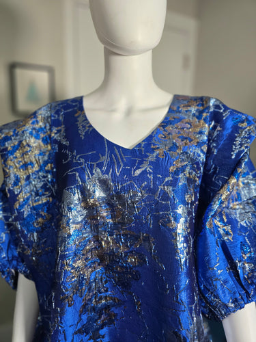 Mannequin wearing a blue and gold patterned dress against a neutral background