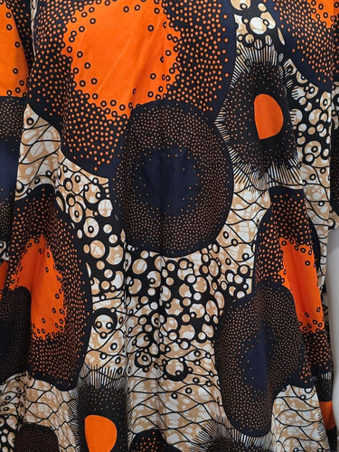 Mannequin wearing a patterned dress with orange and black circles in a store setting.