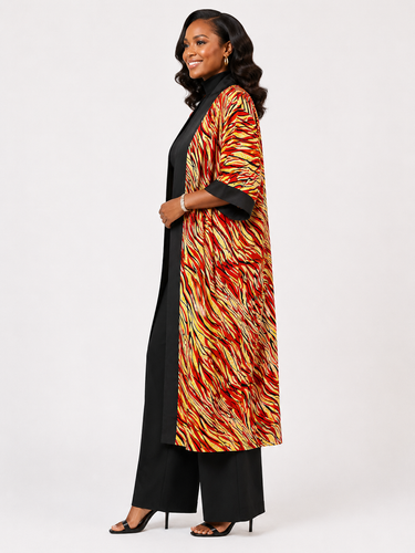 Woman wearing a long, patterned coat over a black outfit on a white background