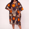Plus size model wearing a bold orange navy and beige Ankara large scale circle medallion print midi dress with V neck wide kimono sleeves and relaxed kaftan silhouette styled with black strappy heeled sandals