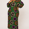 Plus size model wearing a green Ankara bodycon maxi dress with large geometric circle medallion print in orange purple and gold with long sleeves and deep V notch neckline styled with gold strappy heels