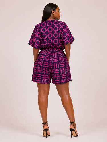 Woman wearing a purple and pink patterned outfit on a light pink background
