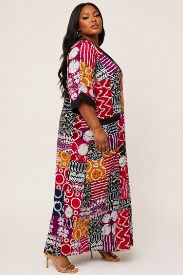 Close up of bold multi motif Ankara print in red orange magenta and navy on a flowy plus size African print caftan maxi dress with contrast black cuffs