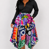 Full length view of a bold multicolor African print patchwork skirt featuring mixed Ankara motifs in purple green orange navy magenta and yellow with a dramatic flowing handkerchief cut asymmetric hem