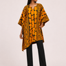 Woman wearing a patterned orange and black top with black pants on a white background