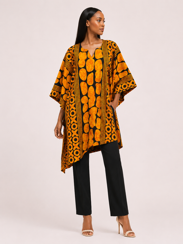 Woman wearing a patterned orange and black top with black pants on a white background