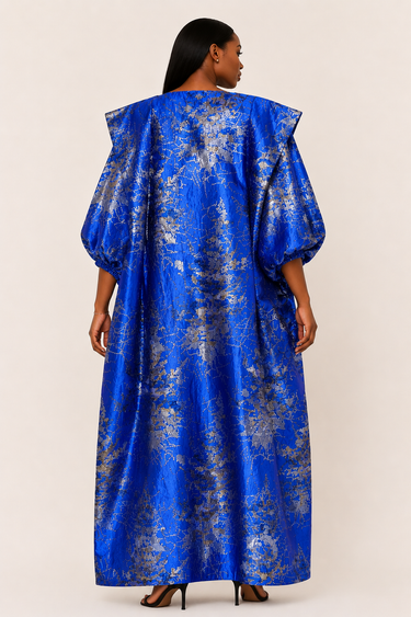 Woman wearing a blue and silver patterned dress against a white background