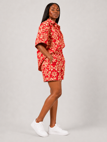 Full length view of a bold red African print co ord two piece set featuring a geometric medallion Ankara pattern on an oversized button down shirt and matching shorts