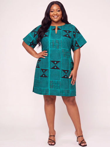 Plus size model wearing a bold teal and black geometric Ankara print short shift dress with keyhole neckline short flutter sleeves and A line silhouette styled with black strappy heeled sandals against a white background
