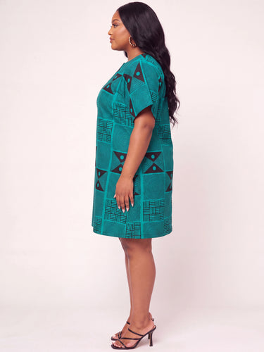 Full length view of a teal and black African print short dress featuring a structured geometric Ankara pattern with spiral circles triangle motifs and basket grid designs in a relaxed plus size A line shift silhouette
