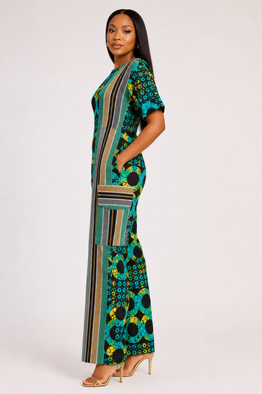 Full length view of an Ankara and Aso Oke mixed fabric wide leg jumpsuit featuring a vibrant teal yellow and black African circle print body with a bold architectural diagonal woven stripe panel accent across the right side