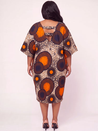 Back view of a plus size Ankara midi dress showing an open cutout back neckline detail in bold orange navy and beige large scale circle print African fabric with wide kimono sleeves and midi length hem
