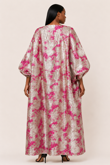 Woman wearing a pink and white floral dress against a plain background