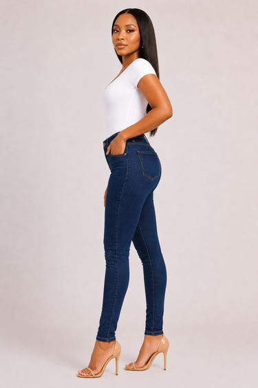 Full length view of deep indigo high waist dark wash stretch denim skinny jeans with golden contrast stitching slim fitted silhouette and classic five pocket construction showing a clean polished finish with no distressing