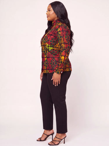 Close up of a geometric circle medallion diamond grid Ankara print in red green and yellow on a fitted plus size African print button down peplum top with white contrast button closure