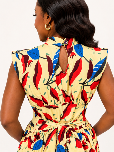 Woman wearing a colorful patterned dress with a plain background
